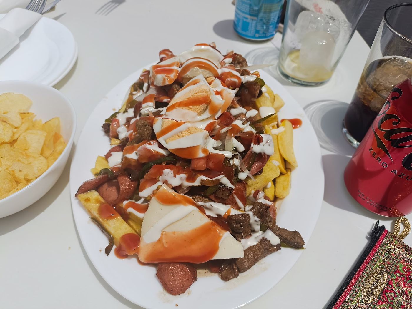 Papas fritas con carne guisada, salchichas, huevo cocido y salsas